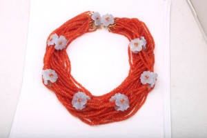 A necklace with orange beads and white flowers.