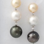 A pair of earrings with pearls and diamonds.