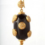 A black and gold earring with white stones.