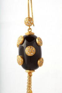 A black and gold earring with white stones.