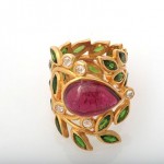 A gold ring with green leaves and a pink stone.