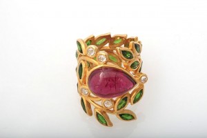 A gold ring with green leaves and a pink stone.
