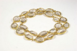 A gold necklace with clear stones on it.