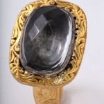 A gold ring with a large black stone on top of it.