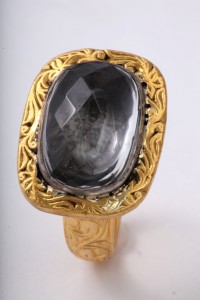 A gold ring with a large black stone on top of it.
