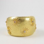 A gold bracelet with some small flowers on it