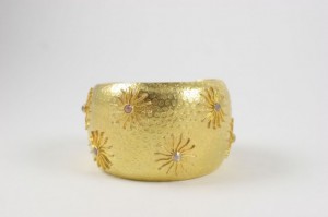 A gold bracelet with some small flowers on it
