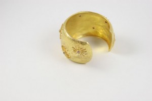 A gold bracelet with a flower design on it.