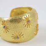 A gold bracelet with stars and stones on it.