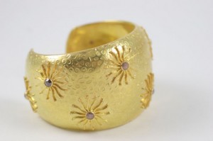 A gold bracelet with stars and stones on it.