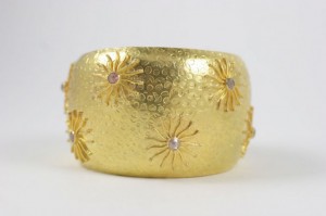 A gold bracelet with five stars and two pearls.