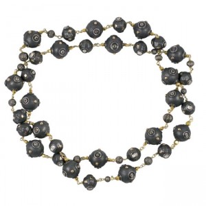 A long necklace with black beads and gold chains.