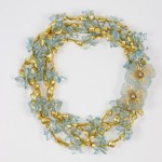 A necklace with gold and blue beads, flowers and pearls.