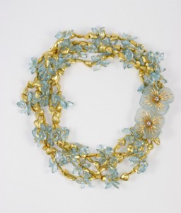 A necklace with gold and blue beads, flowers and pearls.