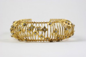 A gold bracelet with flowers and diamonds on it.