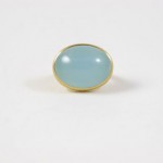 A blue stone is sitting on top of a gold ring.