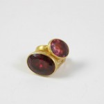 A gold ring with two red stones on it.