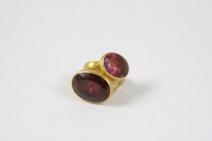 A gold ring with two red stones on it.