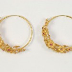 A pair of gold hoop earrings with rubies.