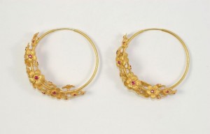 A pair of gold hoop earrings with rubies.