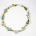 A necklace of green and blue stones with gold beads.