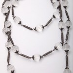 A long necklace with clear beads and black metal accents.