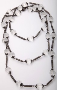 A long necklace with clear beads and black metal accents.