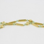 A long necklace with green beads and gold bars.