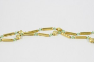 A long necklace with green beads and gold bars.