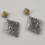 A pair of earrings with chains and yellow stones.