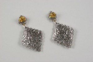 A pair of earrings with chains and yellow stones.