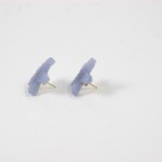 A pair of blue earrings sitting on top of a white surface.