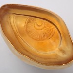 A gold eye bowl with an evil looking eye on it.