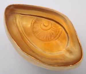 A gold eye bowl with an evil looking eye on it.