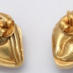 A pair of gold earrings with a design on them.