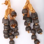 A pair of earrings with gold leaves and black flowers.