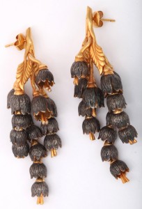 A pair of earrings with gold leaves and black flowers.