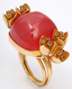 A gold ring with a red stone and five cats.