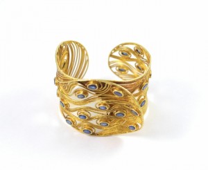 A gold bracelet with blue stones on it.