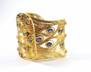 A gold bracelet with blue stones on it.
