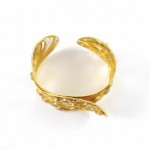 A gold bracelet with a white ball on top of it.