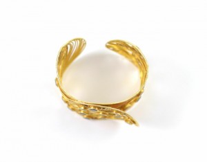 A gold bracelet with a white ball on top of it.