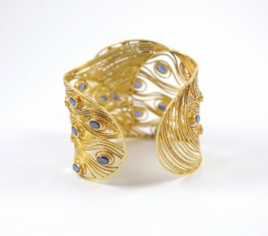 A gold bracelet with blue stones on it.