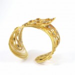 A gold bracelet with a leaf design on it.