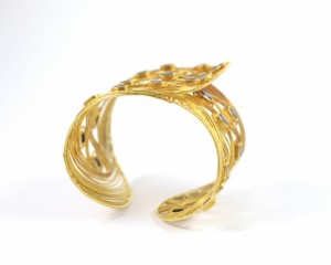 A gold bracelet with a leaf design on it.