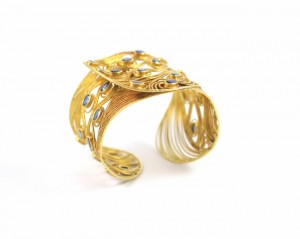 A gold bracelet with a diamond and blue stone.