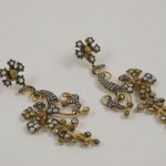 A pair of earrings with gold and diamond flowers.