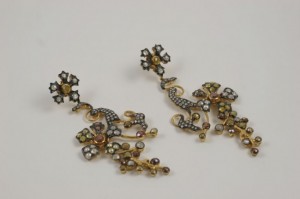 A pair of earrings with gold and diamond flowers.