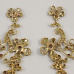 A pair of gold earrings with a floral design.