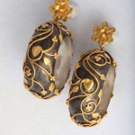 A pair of earrings with gold and black design.